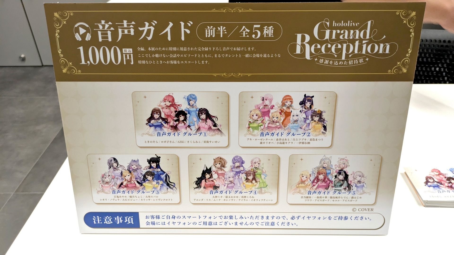 hololive Grand Reception会場の音声ガイド案内板。前半の全5グループと料金が掲載されている。